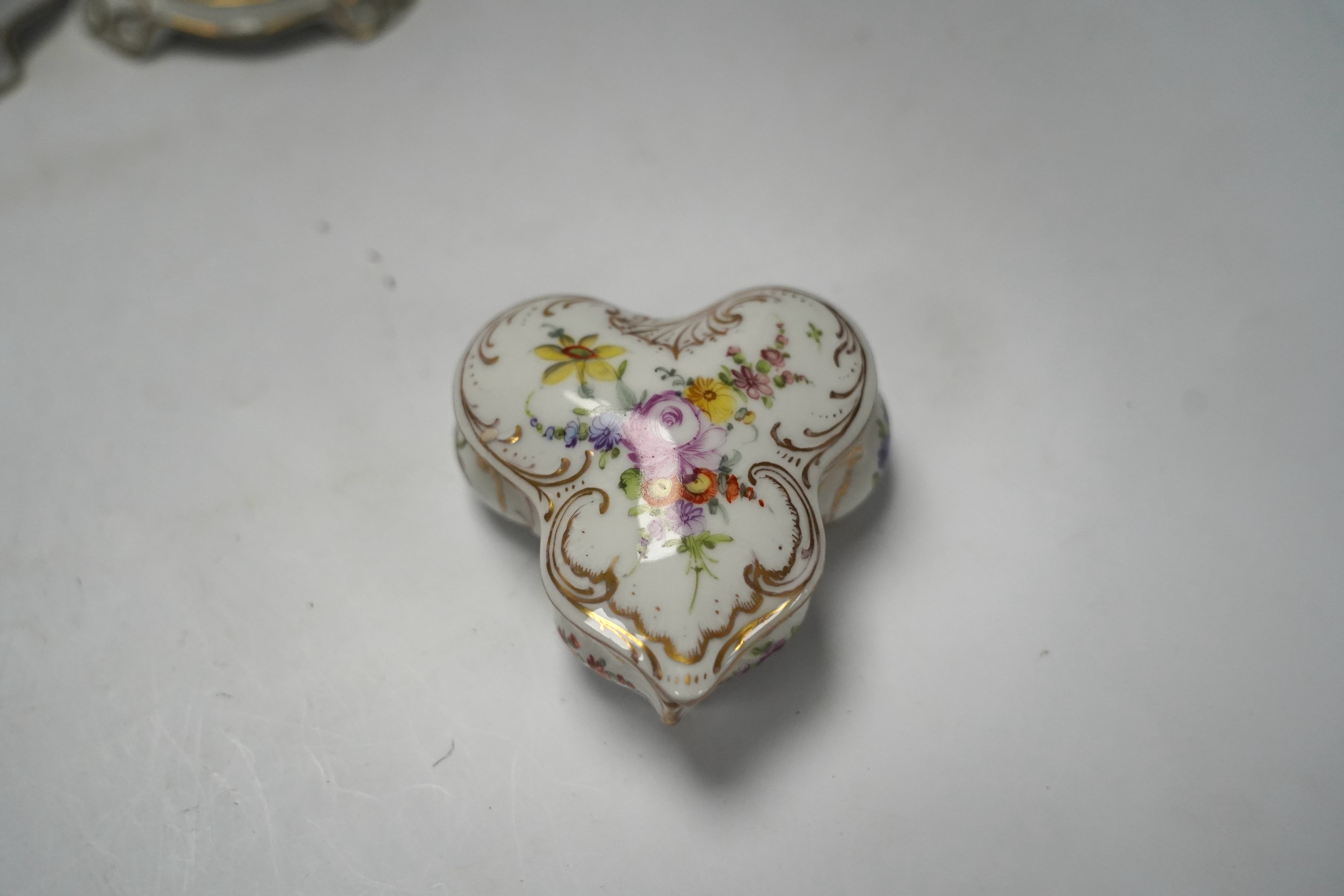 A porcelain shell-shaped centrepiece, a Dresden pill box, a pair of taper holders and a porcelain figure, tallest 21cm